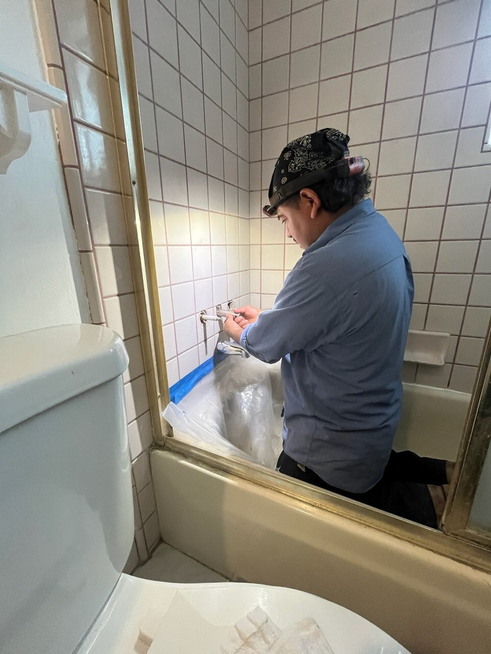 Smart Plumber technician repairing a shower faucet inside a tiled bathtub in Mountain View during a residential plumbing service.